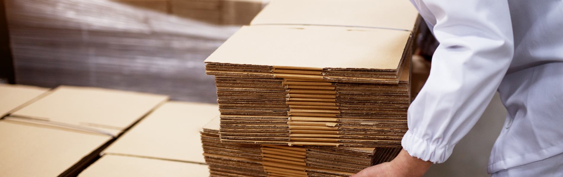 Close Up Of Young Female Worker Picking Up Stacks Of Folded Card