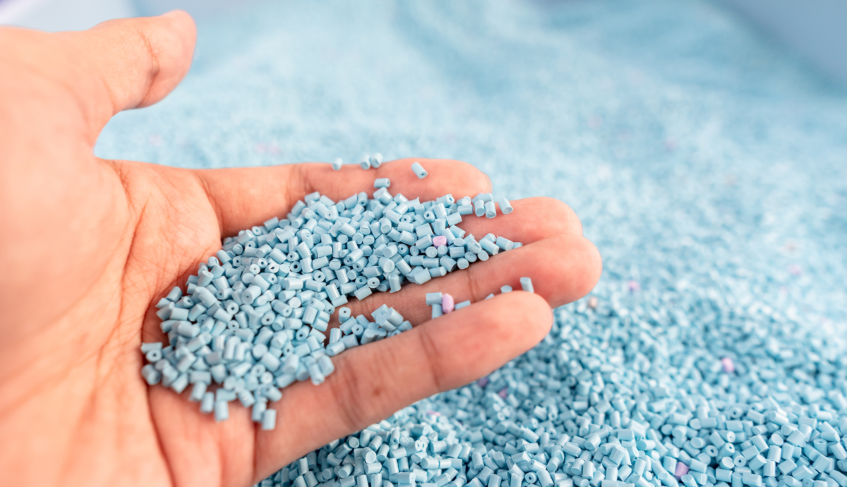 Hand On Large Pile Of Blue Plastic Granules In Temporary Storage