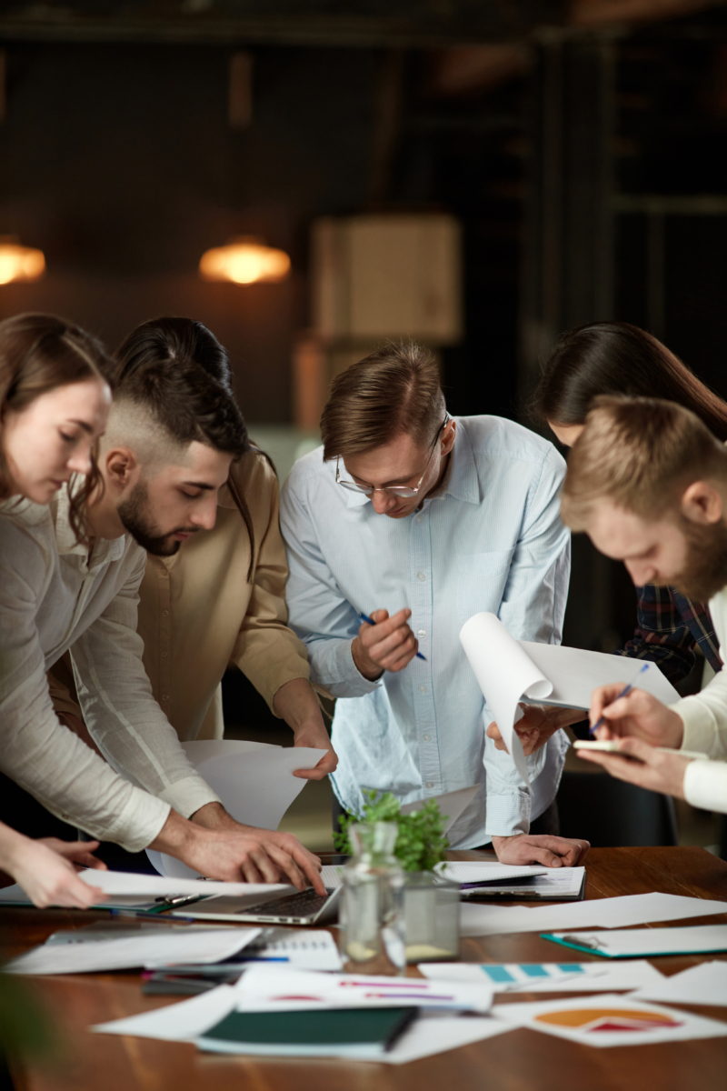 Group Of Young Employees, Managers, Accountants And Designers At Business Meeting In Office Discussing Project, Checking Documents