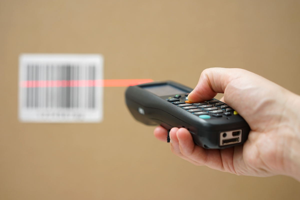 Closeup Of Hand Holding Bar Code Scanner And Scanning Code On Ca